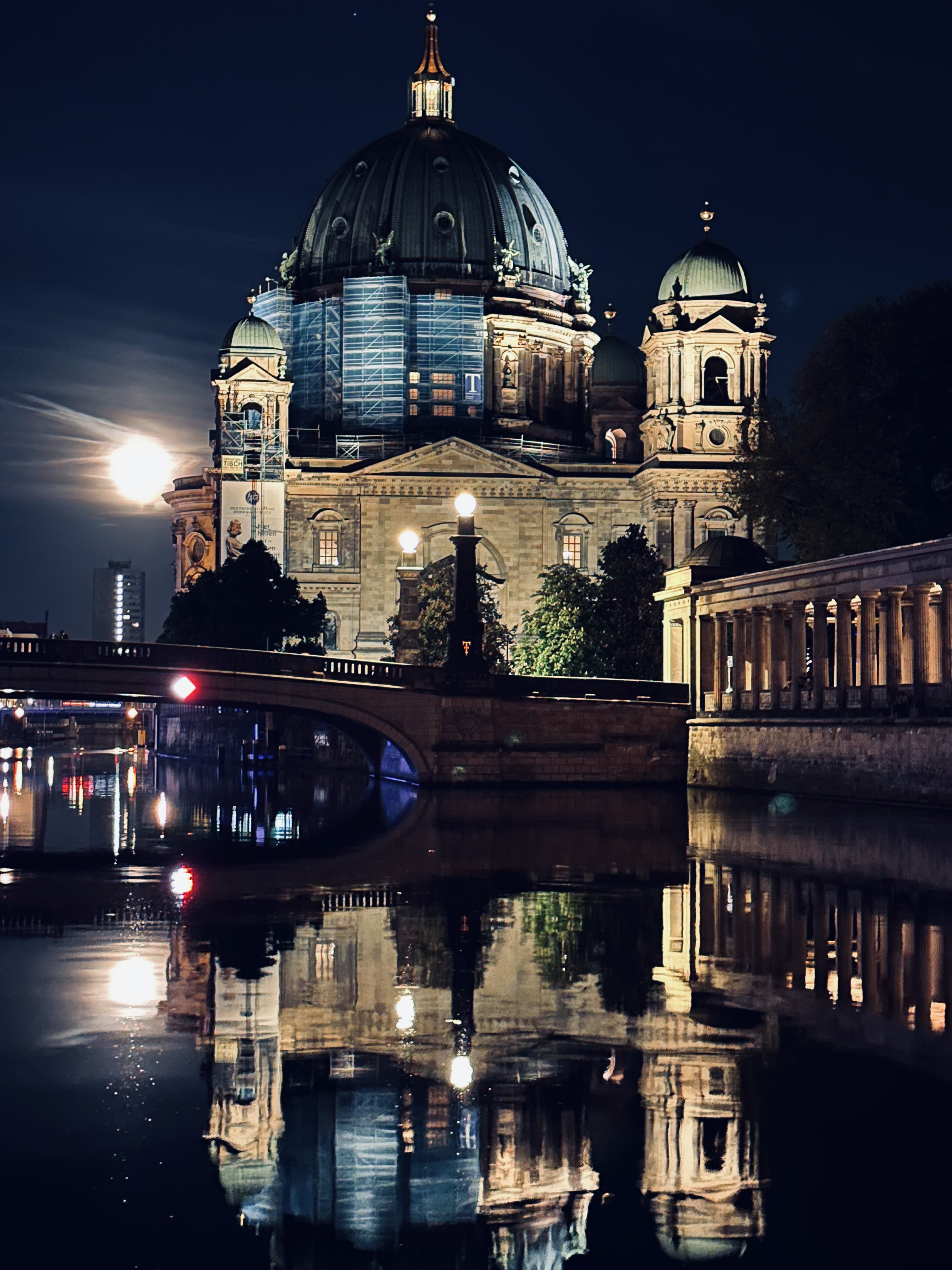 image of berliner dom at night with its reflection in the river besides it.